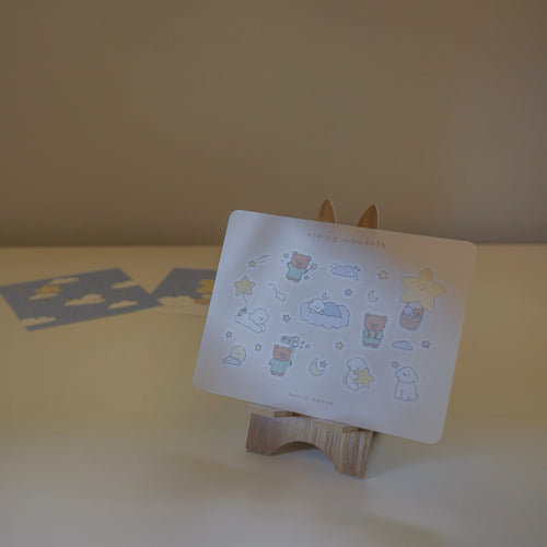 Sticker sheet with cartoon designs on a wooden stand against a plain background.