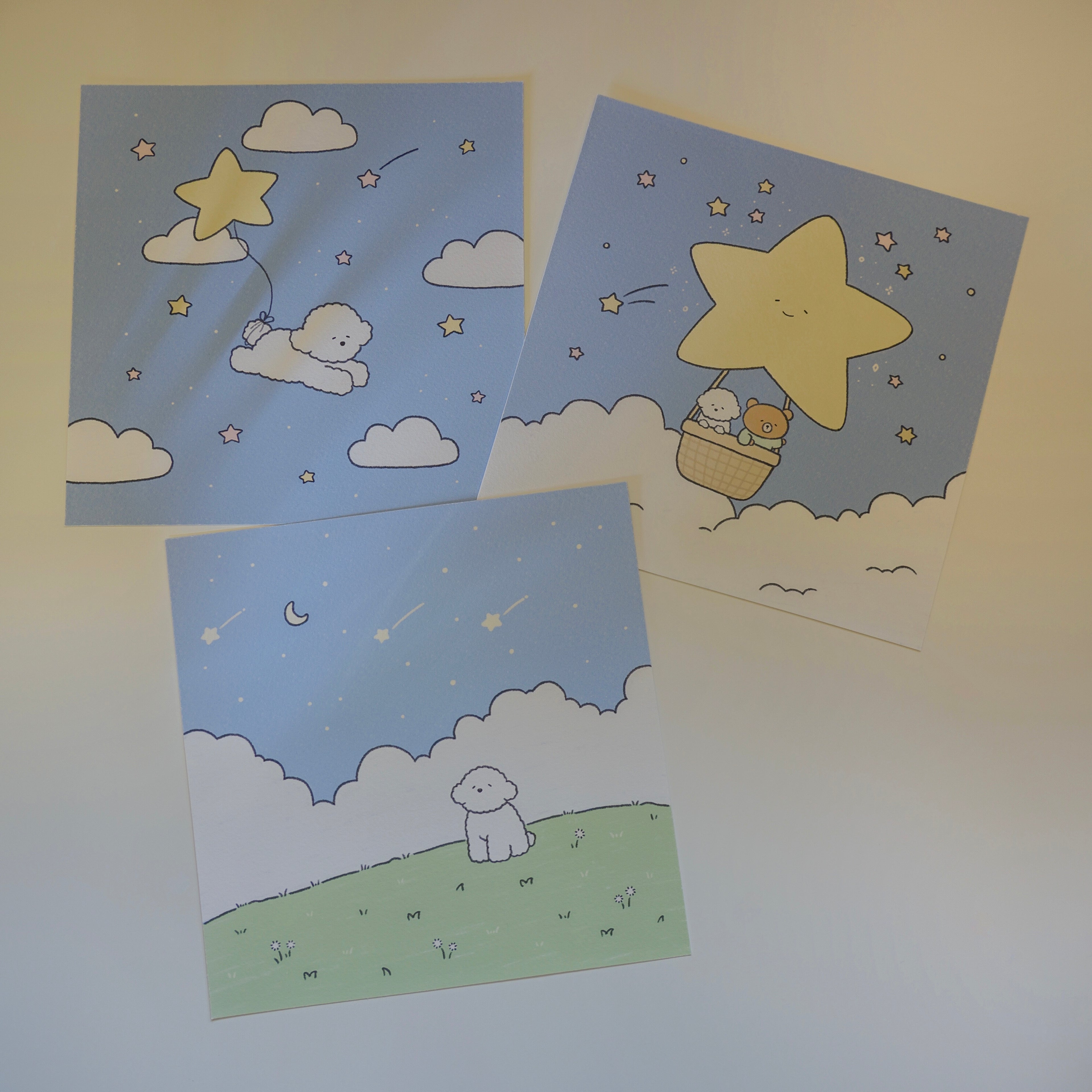 Three art prints with cute designs of a bear, dog, and stars on a light blue background.
