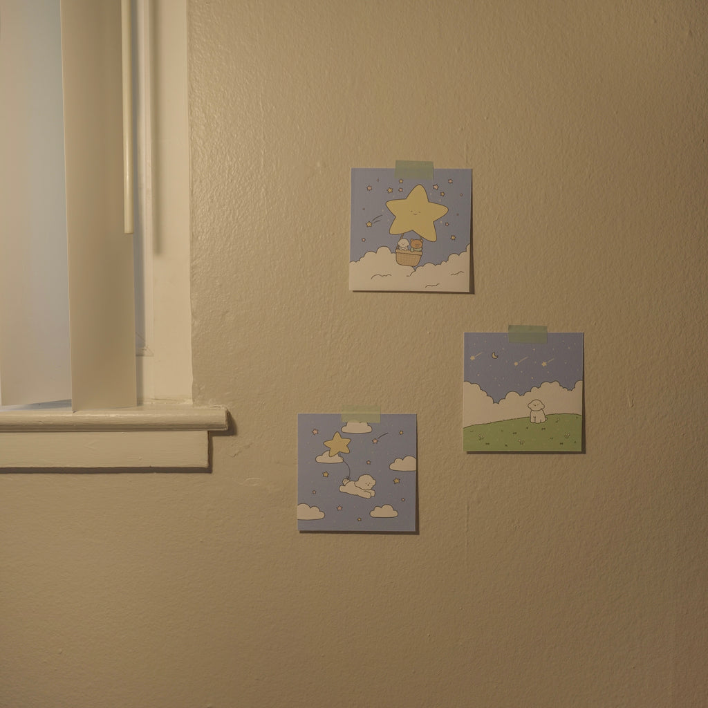 Three small prints on a beige wall near a window.