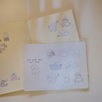 Notebook with cute dog illustrations on a sticker sheet with a light background.